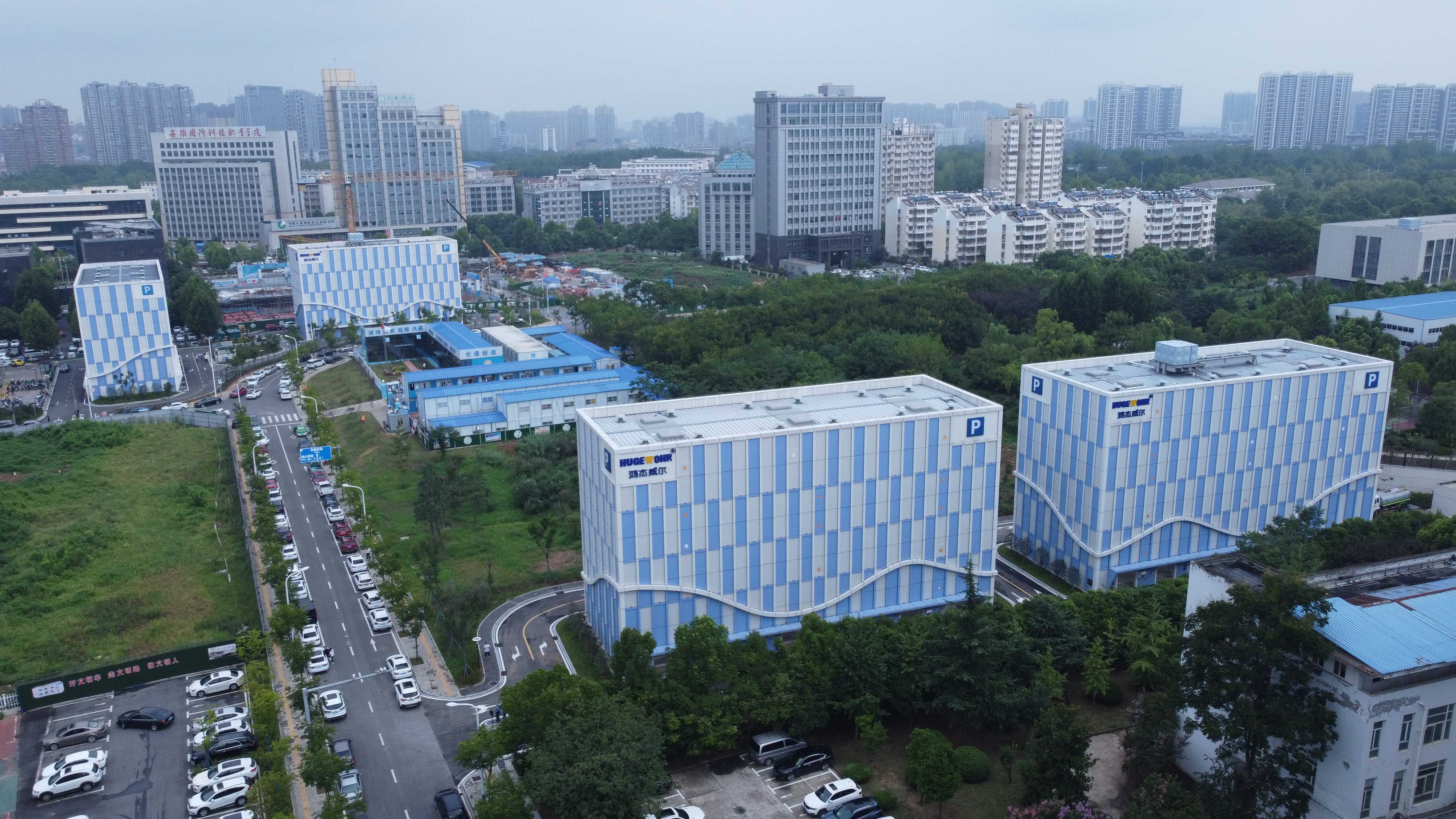 现代化住宅小区建筑群，多层楼房排列整齐，白色墙面配深色屋顶，绿化景观优美，阳光明媚